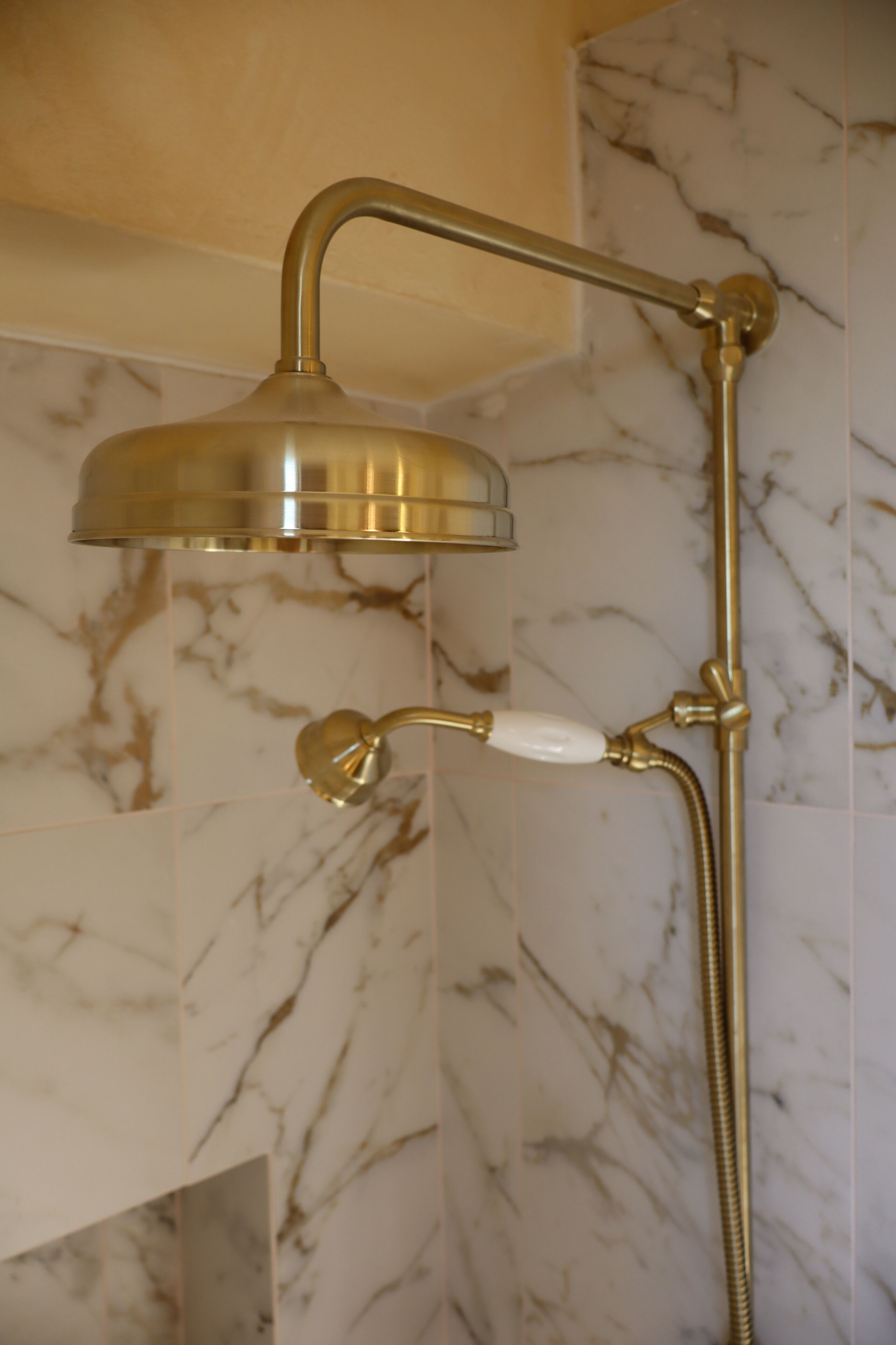 Une douche dotée d’un pommeau de douche incurvé et d’un pommeau de douche à main.