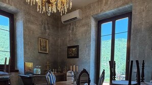 Comedor con candelabro, papel tapiz estampado y ventanas amplias.