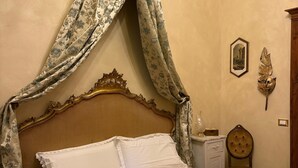 A bed with a canopy, a bedside table, a chair, and a wall-mounted air conditioner. - A restored 1845, luxury 5-bedroom Palace with AC in Medieval Fivizzano, Italy (Fivizzano)