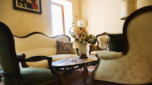 Una habitación con sofá, dos sillones, una mesita y un florero con flores.