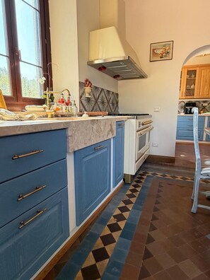 A kitchen with blue cabinets, a stove, and a window.