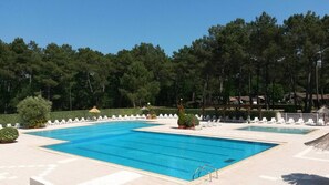 A swimming pool with lounge chairs and a small bridge, surrounded by trees. - Maisonnette de 3 chambres, dans un village vacances à Gujan-Mestras. (Gujan-Mestras)