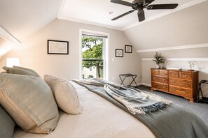 Un dormitorio con cama, cómoda, ventilador de techo y ventana.