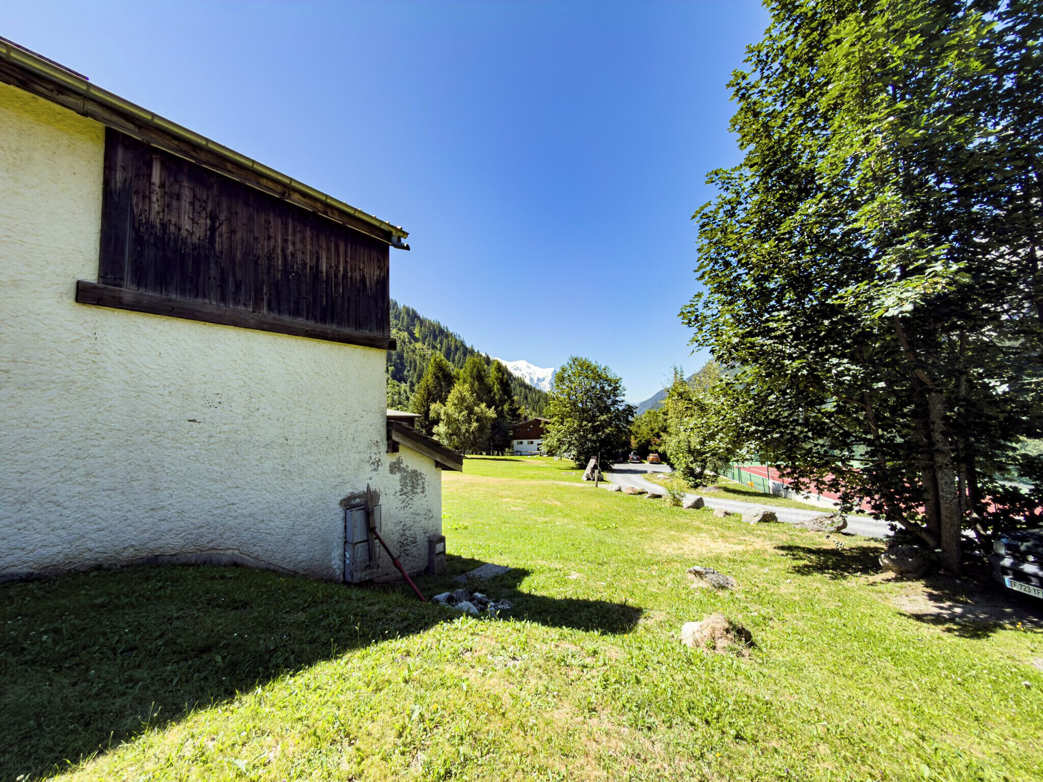 Une propriété rurale avec un bâtiment blanc, une cour verdoyante et un arbre.