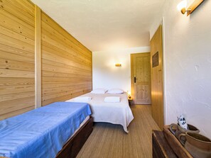 Una habitación con dos camas, paredes de madera, una mesita de noche con una lámpara y una puerta con un letrero.