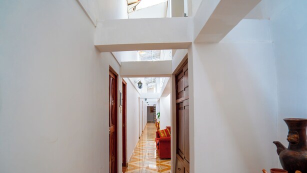 Un pasillo con suelo de baldosas, puertas de madera y vista a una habitación con un sofá.
