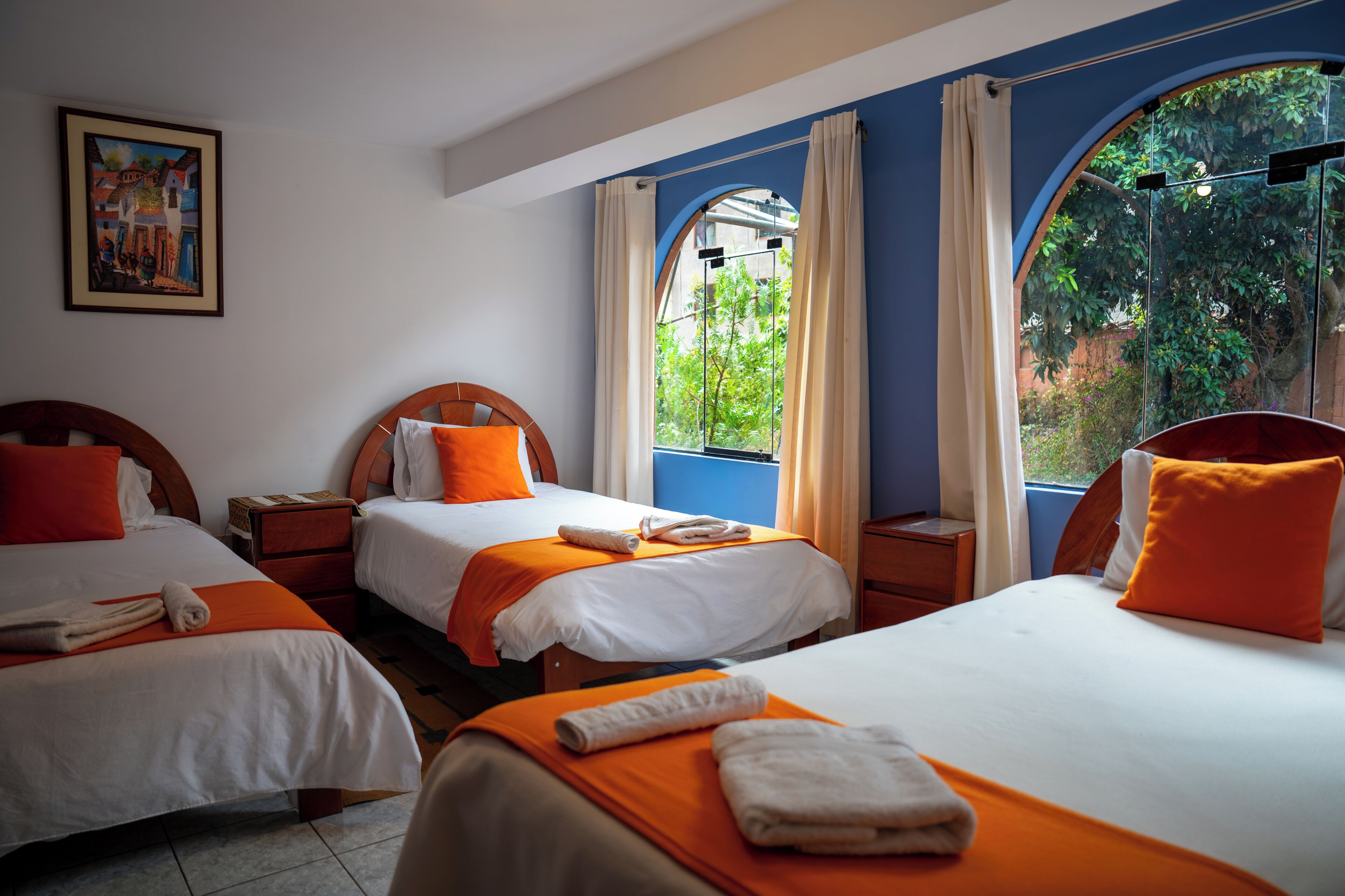 Habitación de hotel con dos camas, un cuadro en la pared y vistas a zonas verdes a través de las ventanas.