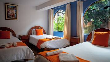 Habitación de hotel con dos camas, un cuadro en la pared y vistas a zonas verdes a través de las ventanas.