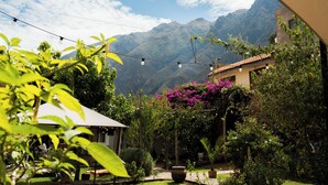 Un jardín con vistas a las montañas, un patio y luces colgantes.