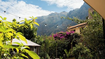 Un jardín con vistas a las montañas, un patio y luces colgantes.