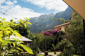 Un jardín con vistas a las montañas, un patio y luces colgantes.