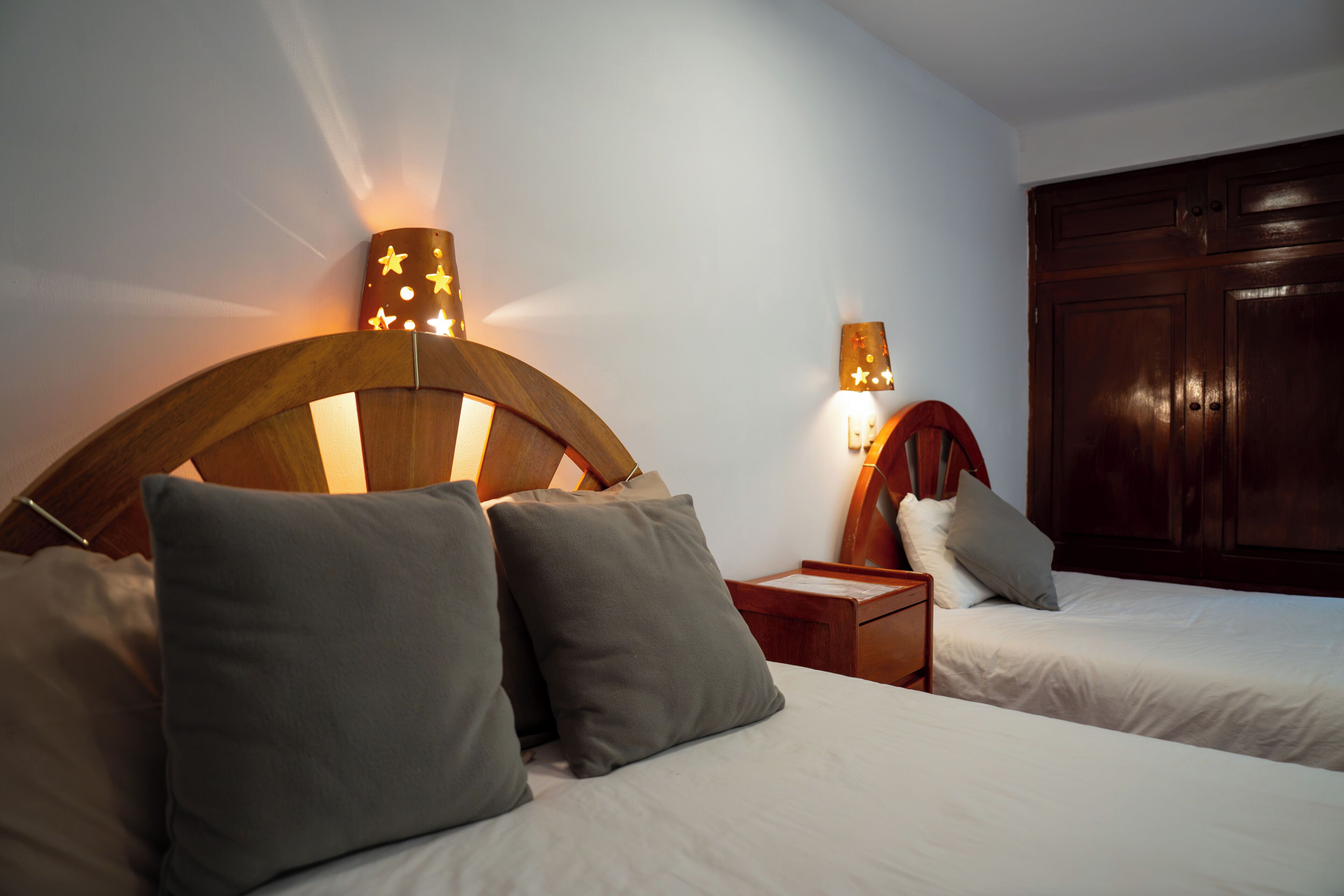 A hotel room with two beds, wooden headboards, and bedside lamps.