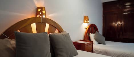Habitación de hotel con dos camas, cabeceros de madera y lámparas de noche.