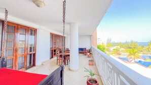 A balcony with a red table, potted plants, and a view of the sea. - Mvuto mzuri Beachfront Apartments (Mombasa)
