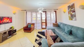 A living room with a flat-screen TV, a sofa, a chair, and a coffee table. - Mvuto mzuri Beachfront Apartments (Mombasa)