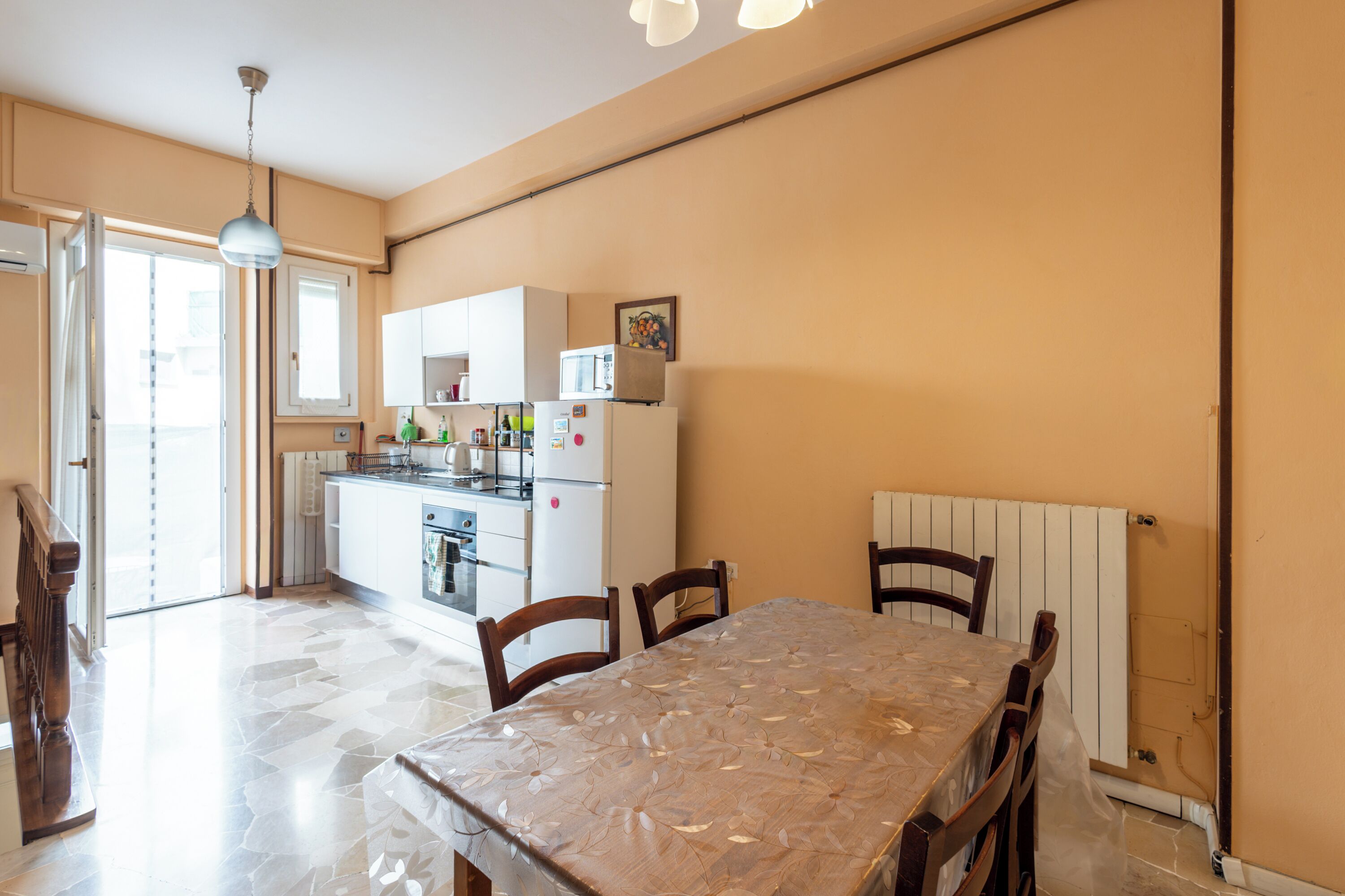 A compact kitchen with a dining table, chairs, and a refrigerator.