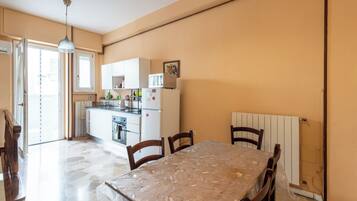 A compact kitchen with a dining table, chairs, and a refrigerator.