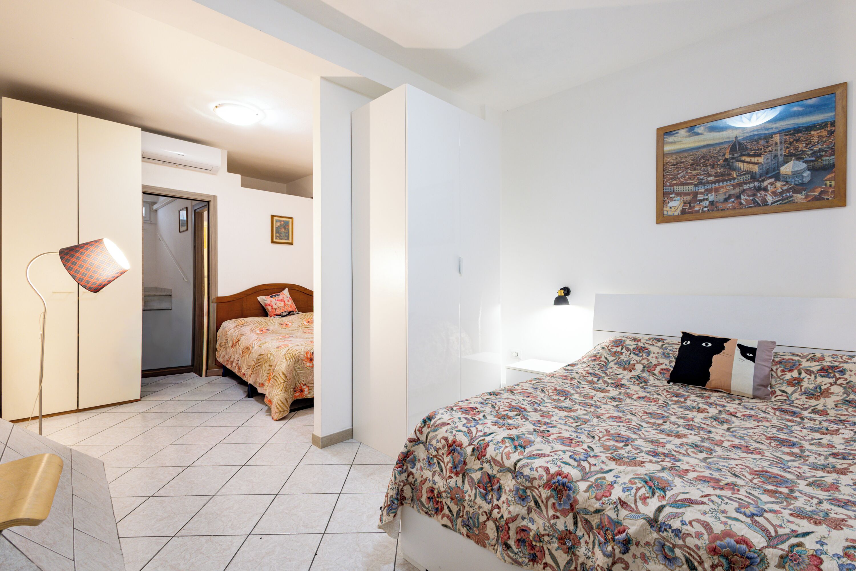 Ein Schlafzimmer mit einem Bett, einem Sessel, einem Schreibtisch und einem Bild an der Wand.