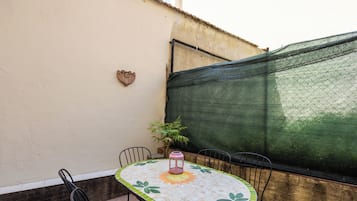 Un patio con una mesa redonda, cuatro sillas, una maceta y un adorno en la pared.