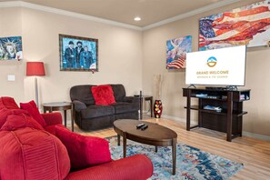 A living room with a sofa, a coffee table, a TV, and artwork on the walls. - The Red Curtain Lakefront (Hollister)