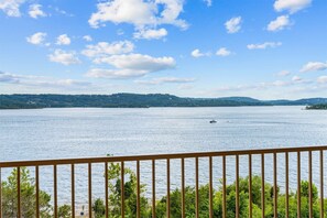 A view of a large body of water with a distant shoreline, a boat, and a railing in the foreground. - Yakov's Hideaway Lakefront (Hollister)