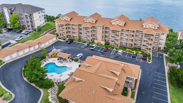 Ein mehrstöckiges Hotel mit Schwimmbad, Parkplatz und Seeblick.