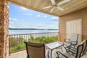 A balcony with a table and chairs, overlooking a body of water and distant land. - Yakov's Hideaway Lakefront (Hollister)
