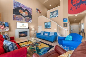 Ein Wohnzimmer mit Kamin, blauen Sofas und verschiedenen Kunstwerken an den Wänden.