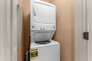 Eine Waschmaschine mit Frontlader in einem Waschraum mit beige gefärbten Wänden und einer Tür.