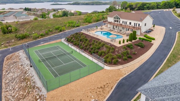 Ein Wohnhaus mit Tennisplatz, Schwimmbad und einem großen Haus mit Balkon mit Blick auf das Schwimmbad.