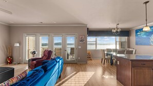 Ein geräumiger Wohnbereich mit einem blauen Sofa, einem Esstisch mit Stühlen und einer Küchenzeile mit Holzschränken.