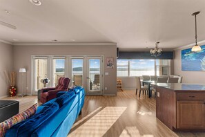 Ein geräumiger Wohnbereich mit einem blauen Sofa, einem Esstisch mit Stühlen und einer Küchenzeile mit Holzschränken.
