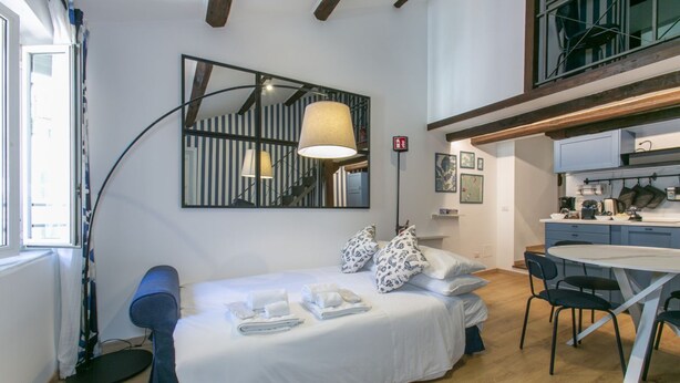 A modern bedroom with a bed, bedside lamps, a desk, and a dining area. - Trevi Little Palace #5 - 52 Steps - no elevator (Rome)