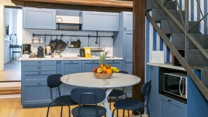 A compact kitchen with blue cabinets, a round dining table with four chairs, and a fruit bowl on the table. - Trevi Little Palace #5 - 52 Steps - no elevator (Rome)