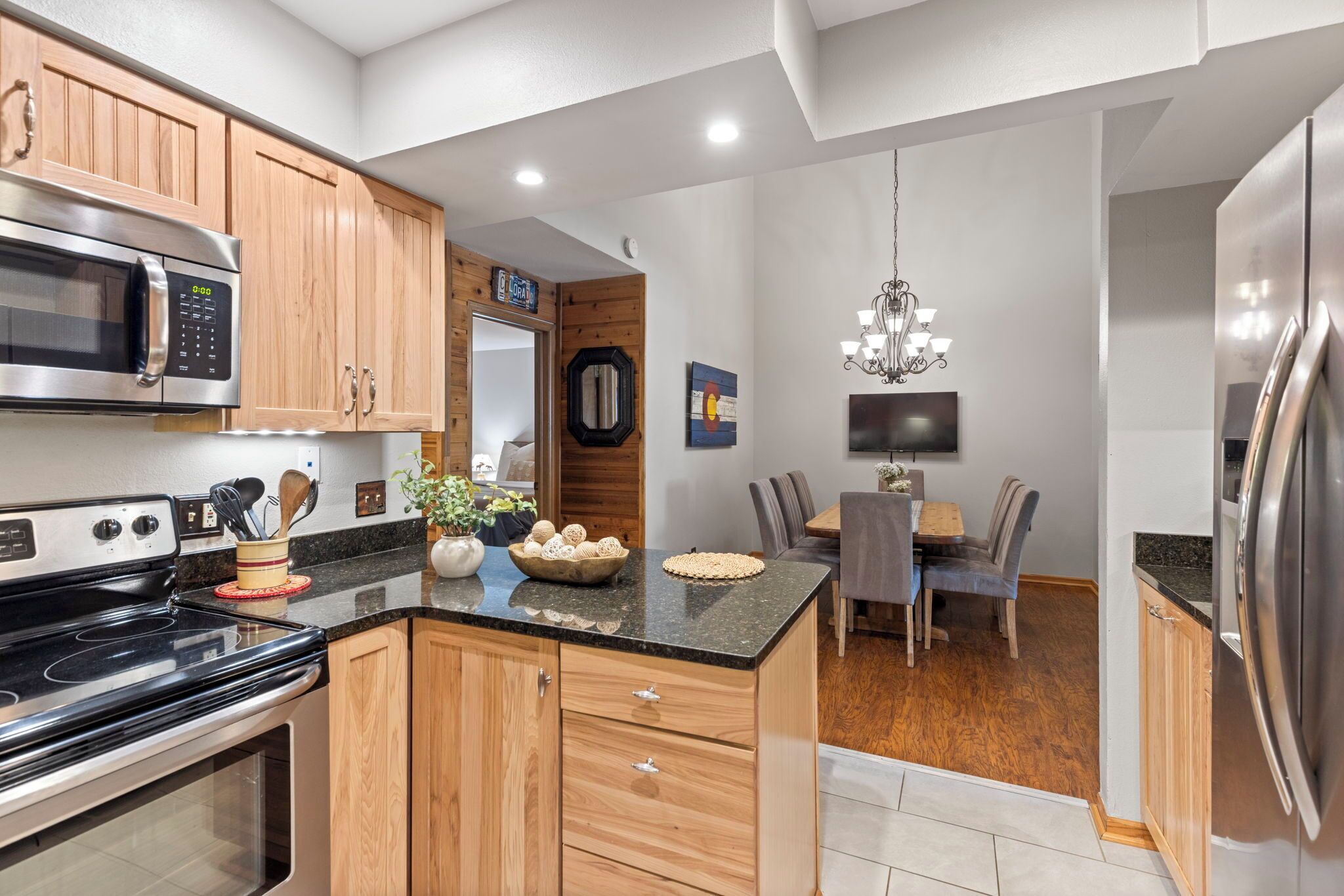 A modern kitchen with wooden cabinets, a stainless steel refrigerator, a microwave, and a stove.