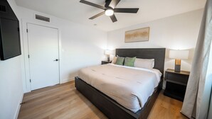 Una camera da letto moderna con un letto, lampade da comodino, una ventola a soffitto e una porta.