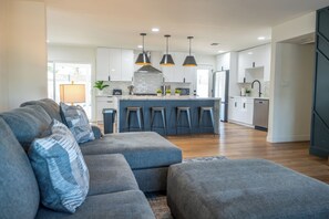 A modern living room with a grey sofa set, a kitchen with white cabinets, and a central island with bar stools. - -- Heated Pool -- The Ultimate Scottsdale Hangout - 3 Bedroom Sleeps 10 (Scottsdale)
