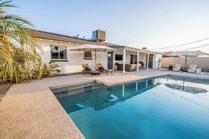 A swimming pool with lounge chairs and umbrellas, surrounded by a white building with a covered patio. - The Ultimate Scottsdale Hangout - 3 Bedroom Sleeps 10 (Scottsdale)
