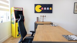 Una sala conferenze con un tavolo in legno, sedie nere, una macchina arcade Pac-Man e un'opera d'arte a tema Pac-Man sulla parete.