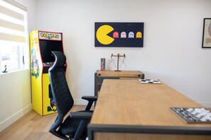 A conference room with a wooden table, black chairs, a Pac-Man arcade machine, and a Pac-Man themed artwork on the wall. - The Ultimate Scottsdale Hangout - 3 Bedroom Sleeps 10 (Scottsdale)