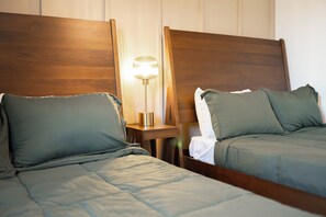 Ein Hotelzimmer mit zwei Einzelbetten, einem Nachttisch mit Lampe und einem Spiegel.