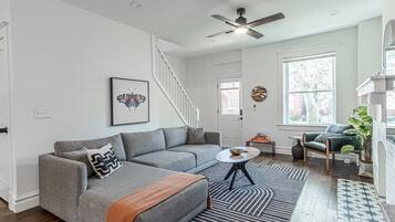 A modern living room with a grey sectional sofa, a round coffee table, and a patterned rug.