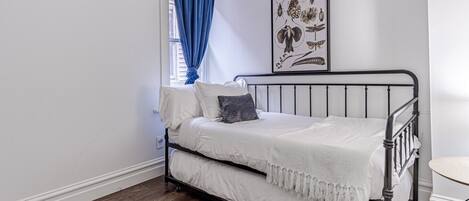 Flexible Sleeping Space: Enjoy a comfortable stay tailored for extra guests or kids in this bright bedroom space, complete with a stylish wrought-iron daybed frame, plush accent pillows, and blackout window coverings for maximum privacy.