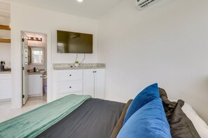 Ein Schlafzimmer mit einem Bett, einem an der Wand montierten Fernseher und einem durch eine offene Tür einsehbaren Badezimmer.