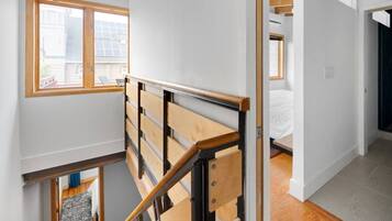 Una escalera con barandillas de madera y vistas a un dormitorio con cama y ventana.