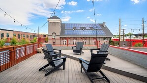 A rooftop deck with outdoor seating and solar panels.