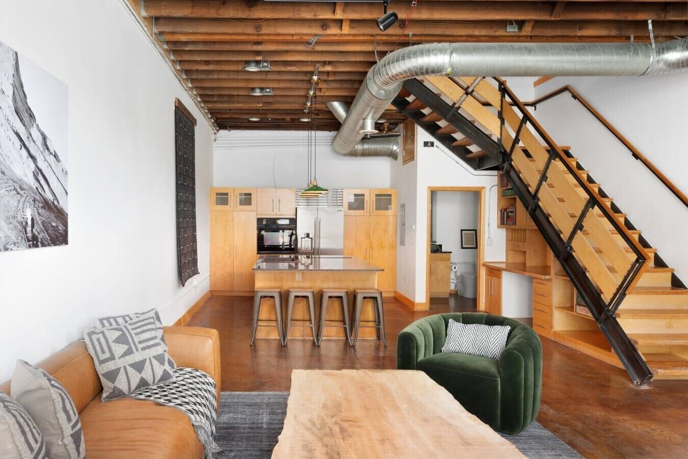 A modern interior with a kitchen, dining area, and a staircase.