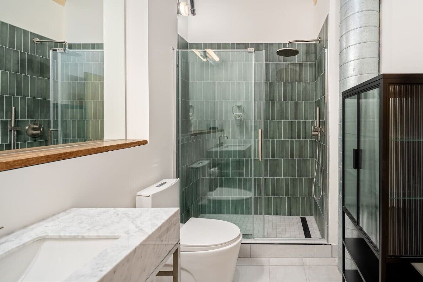 A modern bathroom with a glass-enclosed shower, a white toilet, and a marble sink.