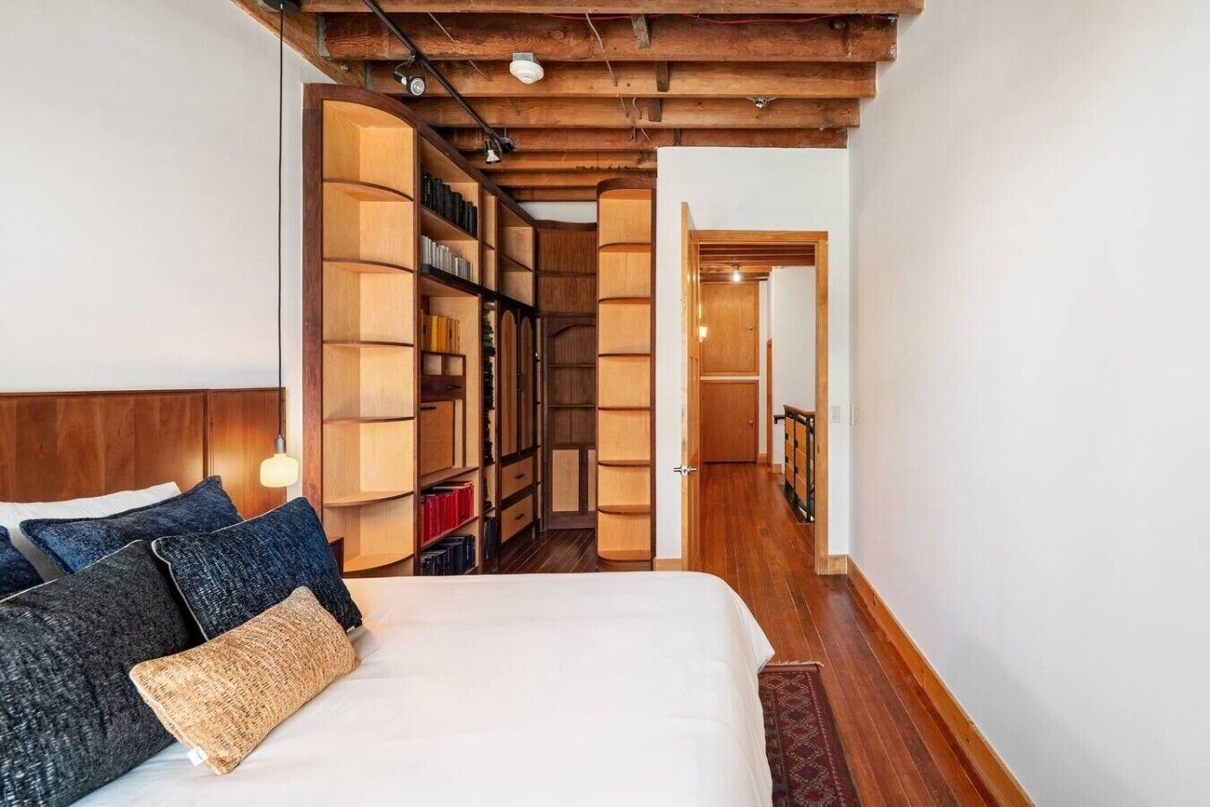 Un dormitorio con una cama grande, estanterías de madera y techo de madera.