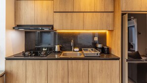 A modern kitchen with wooden cabinets, a black stove, stainless steel sink, and a GE refrigerator.